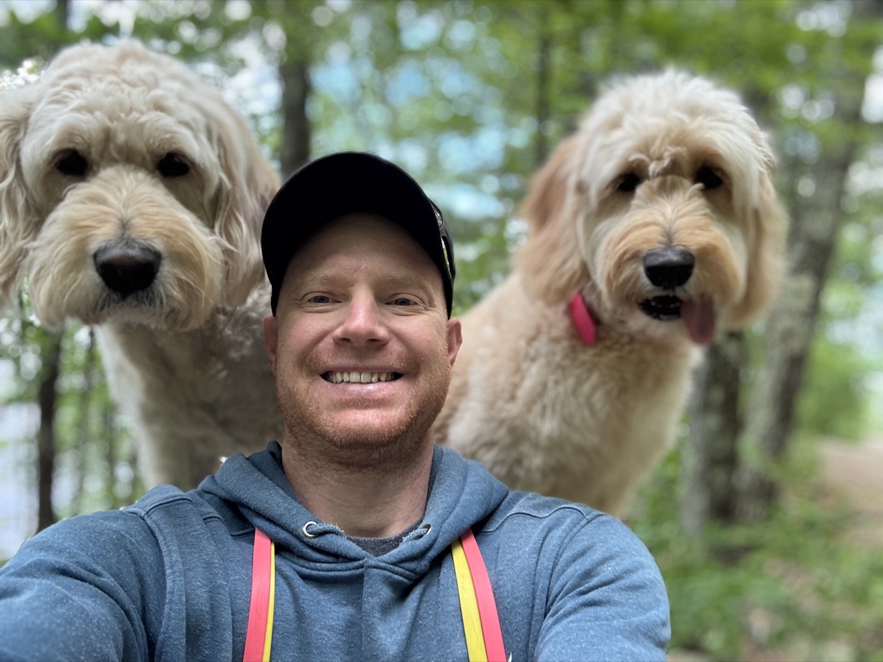Jake, founder of Wag & Wheels, with his two Goldendoodles on a trail walk